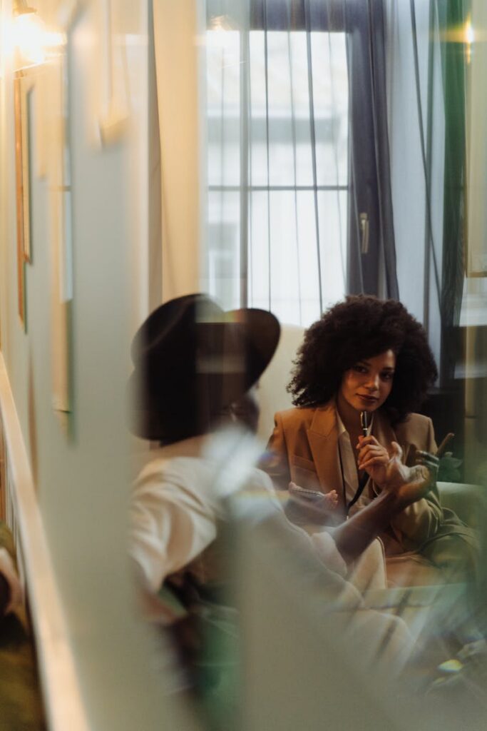 Two individuals engage in a cozy, stylish indoor conversation with a modern, artistic vibe.